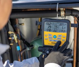 Technicien mesurant les valeurs du fluide frigorigène d’une pompe à chaleur à l’aide d’un manifold numérique Fieldpiece
